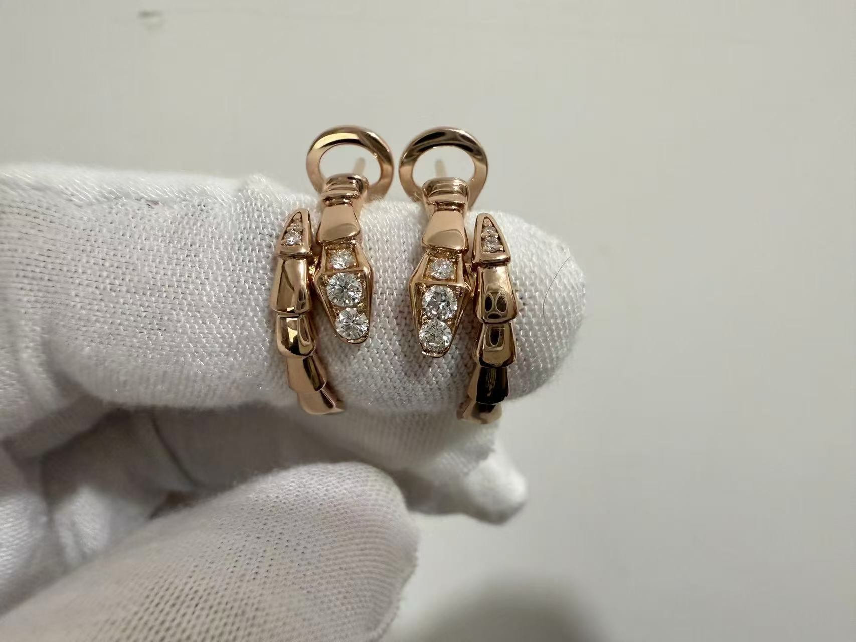 Rose-tone Serpenti Viper style replica earrings with polished segments and clear stones at the ends