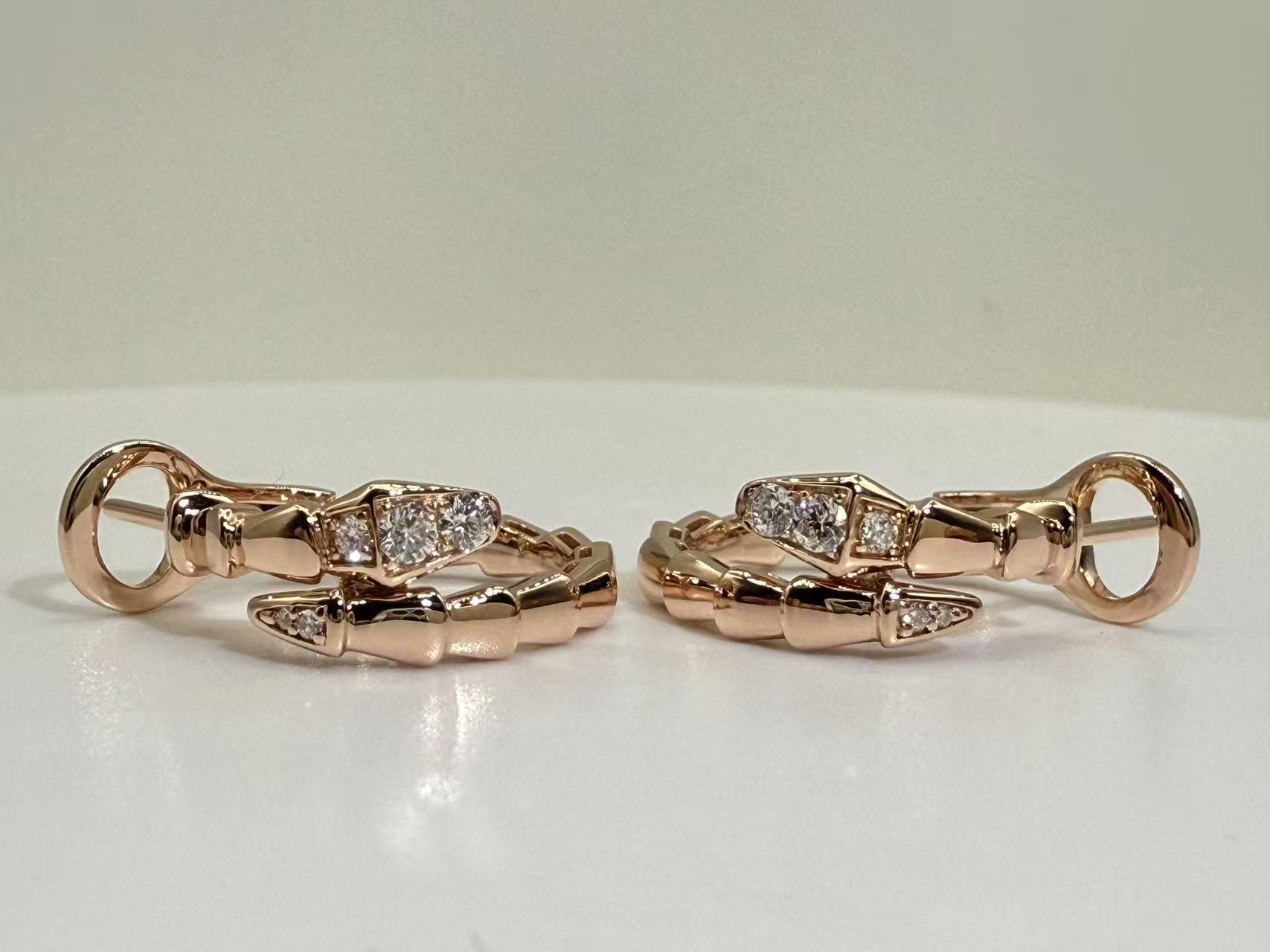 Side view of two rose-tone curved hoops showing polished segments, clear stones, posts and round backs